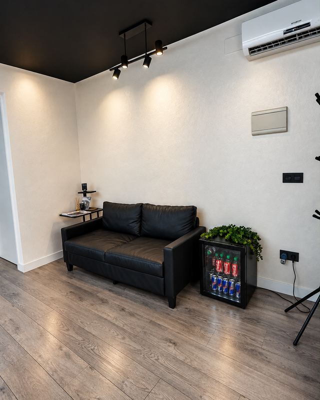 Zona de espera con sofá de piel negro y nevera de bebidas