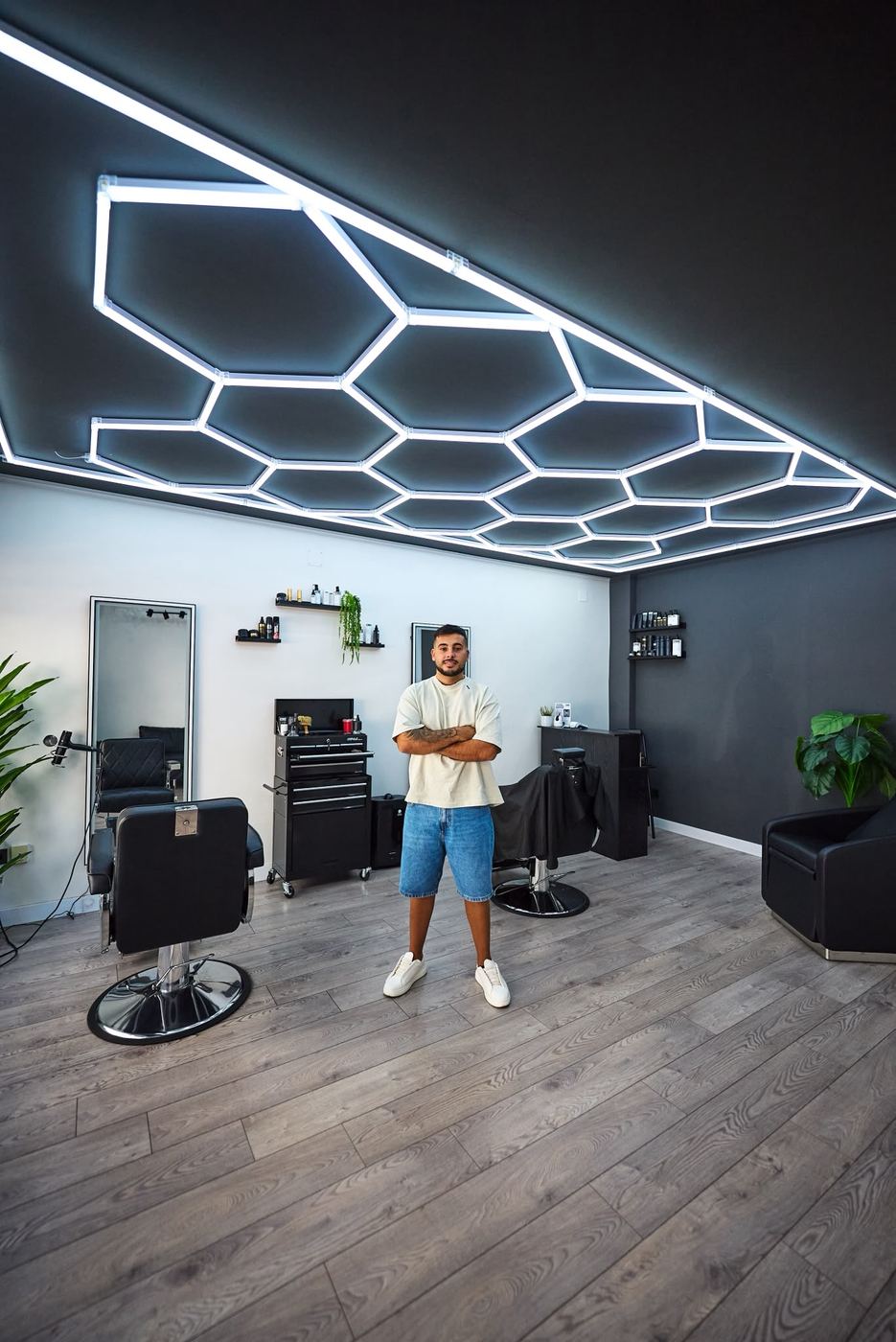 Rafa Acevedo en el interior de Eleganz Barber Studio, bajo el techo de luces hexagonales